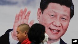 北京街头的习近平大幅照片海报前,有行人走过,有人戴口罩(2017年10月26日)