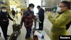 中国浙江省杭州市火车站一名旅客使用手机中的绿色健康码向车站检疫人员显示他的健康状况。(2020年2月17日)