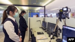 台湾疾病控制中心的工作人员在台北桃园国际机场检测从中国武汉抵达的乘客的体温。(2020年1月13日)