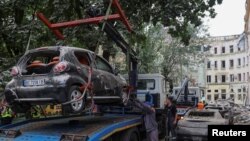 Львів після ннічгого обстрілу. Муніципальні працівники прибирають пошкоджені автомобілі поруч із житловим будинком, який постраждав від російського ракетного удару під час нападу Росії на Україну. Львів, Україна, 6 липня 2023 року. REUTERS/Роман Балюк