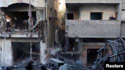 2024年12月13日,巴勒斯坦人在以色列袭击加沙地带中部努塞拉特难民营现场勘察损坏的情况。