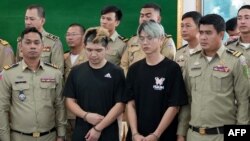 这张由西哈努克省行政当局于2024年2月15日拍摄并发布的传单照片显示,台湾男子陈能钏(中左)和鲁祖显(中右)在西哈努科省的一场新闻发布会上与警方站在一起,他们因播放假绑架视频而被捕。(法新社)