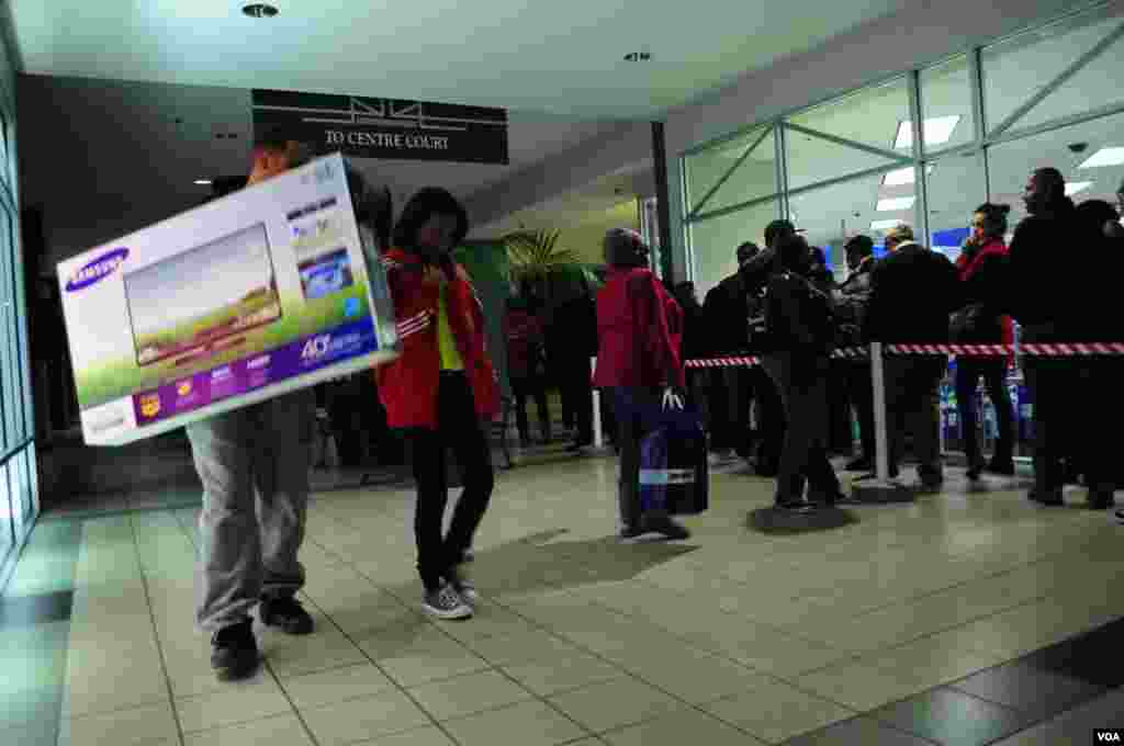 2012年11月22日,在维吉尼亚州阿灵顿,购物者抱着电视离开,其他人则蜂拥进入商店。 (D. Manis/VOA)