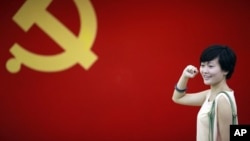 在上海的中共第一次代表大会会址,一名女子在中国共产党党旗下摆出宣誓姿势 (2012年7月1日)