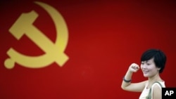 在上海的中共第一次代表大会会址,一名女子在中国共产党党旗下摆出宣誓姿势 (2012年7月1日)