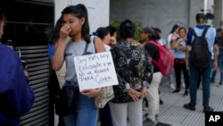 资料照片: 2024年2月5日一名妇女在阿根廷人力资本部长办公室外与其他人一起排队等待援助。标语牌上面西班牙语写着:“我是贝蒂,一名学生,我没有足够的食物”。