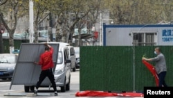 中国官方宣布,新冠疫情得到控制。但是,这一历史性灾难带来的后果正在显现。图为戴着口罩的工人正在拆除武汉街头的障碍物。(2020年3月21日资料照)