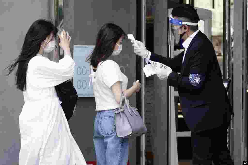 ဂျပန်နိုင်ငံ တိုဂျိုမြို့က Shopping စင်တာတခုထဲ မဝင်ခင် အပူချိန် တိုင်းပေးနေတဲ့ ဝန်တမ်းတဦး။ (ဇွန် ၁၁၊ ၂၀၂၀)