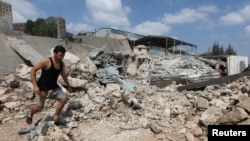 黎巴嫩官方媒体称以色列对黎巴嫩南部城市纳巴泰的一栋住宅大楼发动袭击,一名男子在受损地点的废墟上行走。(路透社:2024年8月17日)