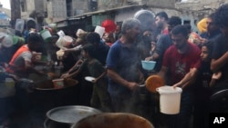 资料照片:在以色列轰炸加沙地带期间,巴勒斯坦人在拉法排队领取食物。(2023年11月13日)