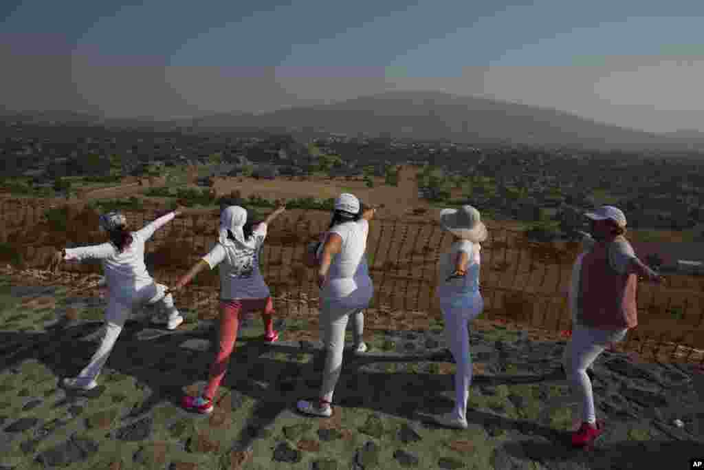 2018年3月21日,墨西哥特奥蒂瓦坎(Teotihuacan)庆祝春分,参观者在太阳金字塔顶上练习瑜伽,看着不远处的月亮金字塔。