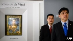 2017年10月13日,被香港媒体认定为前美国中央情报局特工李振成(音译)的男子(右)站在佳士得香港展厅的保安员前面,身后是达芬奇的画作 。