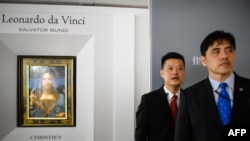 2017年10月13日,被香港媒体认定为前美国中央情报局特工李振成(音译)的男子(打蓝色领带者)站在佳士得香港展厅的保安员前面,身后是达芬奇的画作。