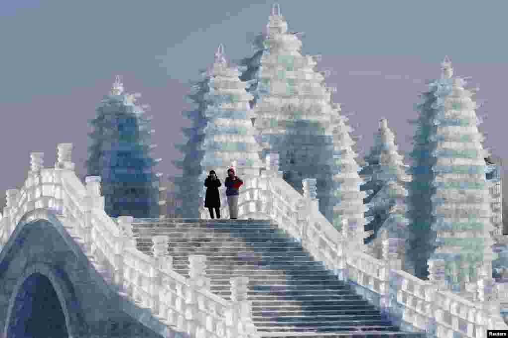在中国东北黑龙江省的哈尔滨国际冰雪节期间,游客走在冰雕桥栏和塔楼之间(2019年1月7日)。哈尔滨简称哈市,别名冰城、東方莫斯科、东方小巴黎。