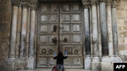 耶路撒冷封城后,一名女子在大门紧闭的老城圣墓教堂前祈祷。(2020年3月30日)
