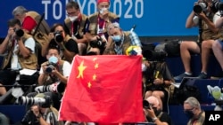巴黎奥运会中国体育代表团于7月13日在北京举行成立大会。中国队在乒乓球和跳水项目将力争“包揽全部金牌”;与此同时,中国游泳运动员兴奋剂检测阳性事件仍未落幕。图为东京奥运会场边观众举中国国旗。