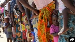 Women and children wait in a queue for oral cholera vaccinations, at a camp for displaced survivors of cyclone Idai in Beira, Mozambique, Wednesday, April 3, 2019.