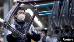 戴着口罩的工人在上海延锋安道拓工厂汽车座椅的生产线上工作。(2020年2月24日)