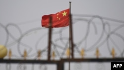 资料照片:在新疆喀什市以南的一个居住区,一面中国国旗在铁丝网后面飘扬。(2019年6月4日)