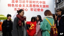 资料照:上海大学生在一幅宣传习近平的大标语前照相后将一面中共党旗收起来。(2017年11月19日)